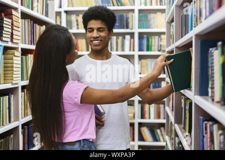 African American boy and girl flirtant à bibliothèque Banque D'Images
