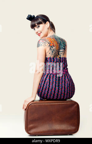 Portrait d'une belle femme avec un style vintage assis sur les bagages Banque D'Images