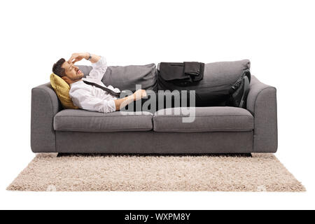 Tourné sur toute la longueur d'un homme allongé sur un canapé-lit après le travail et tenait la tête isolé sur fond blanc Banque D'Images