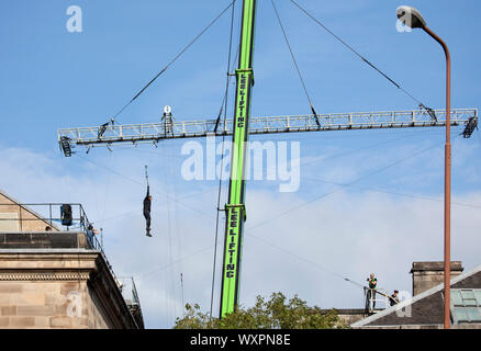 Les toits, West College Street, Édimbourg, Écosse, Royaume-Uni. 17 septembre 2019. Temps clair soleil et ciel bleu pour le tournage de "Fast and Furious 9', sur la photo, film cameraman et acteur cascadeur en suspension dans l'air d'un bras qu'ils fil zip sur la poulie avec une énorme grue, comme cette scène s'est poursuivie pour la deuxième journée, au-dessus du centre-ville rues. Banque D'Images