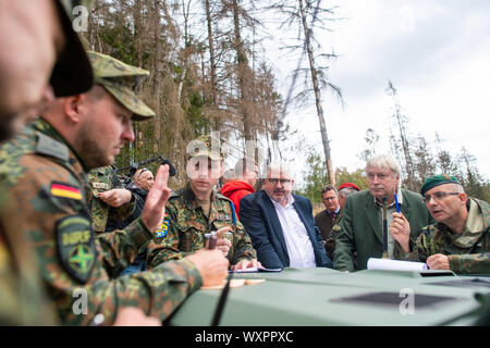 17 septembre 2019, la Saxe-Anhalt, Straßberg : Les soldats du bataillon logistique de 171 de Burg et 172 du bataillon logistique de Beelitz stand avec Lutz-Georg Berkling (l.) du ministère de l'intérieur de la Saxe-Anhalt, Egbert Thile (m.), chef de l'Office des forêts du Harz et du Lieutenant-colonel Bertram Schuster, Coordonnatrice des opérations du Commandement à l'état de Saxe-anhalt le capot d'un véhicule hors route des forces armées allemandes et discuter d'autres actions communes dans la semaine à venir. Les soldats sont les premiers enquêteurs des forces armées allemandes à se renseigner sur leur prochaine de Banque D'Images