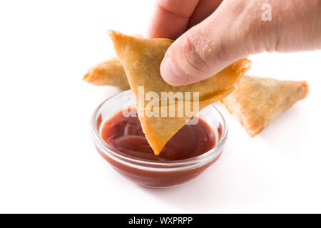 La main avec samosa trempant dans une sauce aigre-douce isolé sur fond blanc. La nourriture traditionnelle indienne Banque D'Images