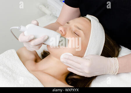 Belle femme recevant l'exfoliation du visage ultrasonique de procédure de nettoyage par ultrasons en face de beauté.L'équipement moderne de la peau par ultrasons Banque D'Images