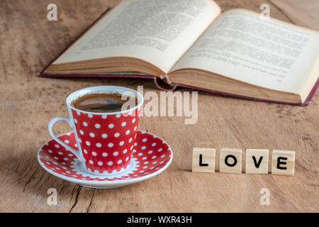 Un livre et une tasse de café sur une table en bois avec la parole d'amour Banque D'Images