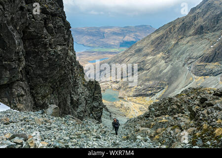 Un marcheur l'ascension de la grande pierre tirer au-dessus de Coire Lagan et Glen cassante. Dans les montagnes Cuillin, ont profité, Isle of Skye, Scotland, UK Banque D'Images