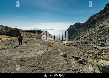 Un marcheur sur glace lisse des pierres sur la lèvre de coco' a'Ghrunnda dans les montagnes Cuillin, Isle of Skye, Scotland, UK Banque D'Images