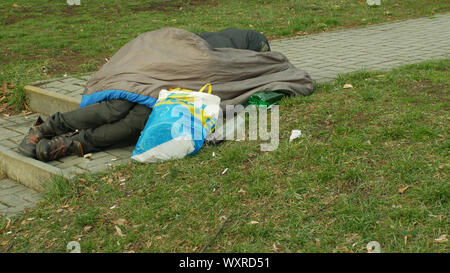 Émotion authentique sans-abri hauts dormir dans un sac de couchage sur la rue près de department store boutique centre commercial, à quelques personnes de la ville de Olomouc, vie Banque D'Images