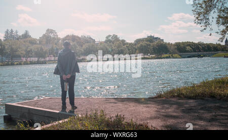 Quelqu'un comité permanent, probablement une femme, vu de derrière, sur le dock pour voir ou méditer tout en admirant le fleuve Avon à Stratford, Ontario. Banque D'Images