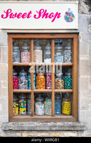 Pots de bonbons dans la fenêtre de guirlandes peu sweet shop. Kingham, Cotswolds, Gloucestershire, Angleterre Banque D'Images