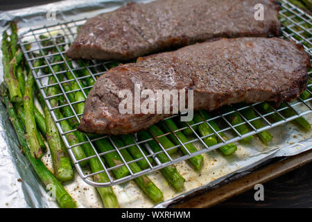 La viande bovine et les asperges grillés sur une feuille pan : de surlonge de bœuf grillés sur un papier aluminium feuille bordée d'asperges avec pan. Banque D'Images