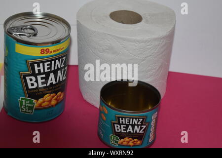 Deux boîtes de baked beans Heinz. 1 grande, 1 petite avec effet sur fond blanc et rose foncé et un rouleau de papier toilette standard de la tourbière. Pets de fibre. Banque D'Images