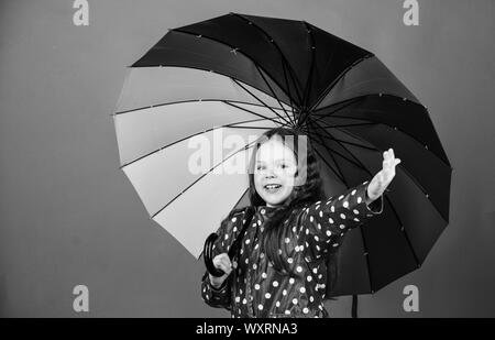 Protection contre la pluie. Arc-en-ciel. automne fashion. bonne petite fille avec parapluie colorés. cheerful hipster enfant dans l'humeur positive. Petite fille en imperméable. Prendre un peu de temps pour se reposer. Banque D'Images