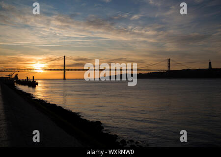 Tage et de la silhouette du Pont 25 de Abril et Sanctuaire du Christ Roi (Cristo Rei) monument à Lisbonne, Portugal, au lever du soleil. Banque D'Images