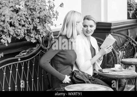 Lecture livre inspirant. Réserver chaque fille devrait lire. Girls friends sitting café terrasse boire du café. La littérature féminine. L'amélioration d'individu et de l'éducation. Discuter de librairie populaire. Banque D'Images