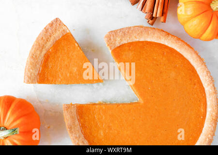 Tarte à la citrouille avec slice retiré. Vue de dessus, gros plan sur un livre blanc en arrière-plan. Banque D'Images