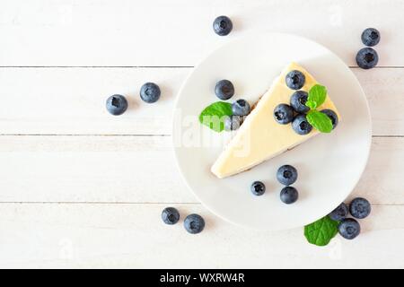 Tranche de gâteau au fromage avec les bleuets. Vue de dessus sur une scène en bois blanc lumineux, arrière-plan. Banque D'Images