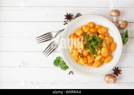 Gnocchis à la courge, sauce à la crème de champignons. Repas d'automne. Vue supérieure de la scène de la table sur un fond de bois blanc. Banque D'Images