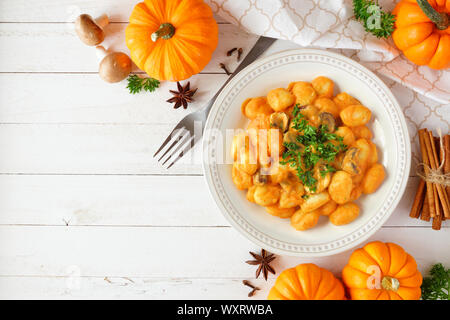 Gnocchis à la courge, sauce à la crème de champignons. Repas d'automne. Vue supérieure de la scène de la table sur un fond de bois blanc avec copie espace. Banque D'Images