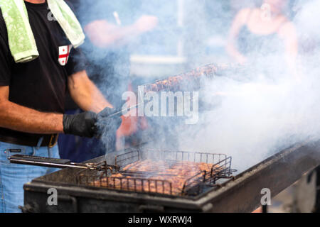 Les faire cuire à la vapeur sur la viande juteuse frites un grill au charbon. L'alimentation et de la cuisine des équipements à un festival de l'alimentation de rue. Banque D'Images