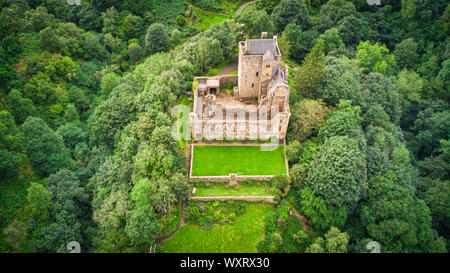 Ancien château situé au milieu des arbres verts et des collines par jour nuageux dans la nature pittoresque Banque D'Images