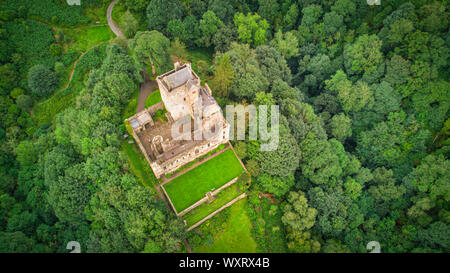 Ancien château situé au milieu des arbres verts et des collines par jour nuageux dans la nature pittoresque Banque D'Images