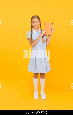 Journal intime pour les filles concept. happy little girl en rétro vintage kid fashion. uniforme. retour à l'école. girl cahier hold ou notepad. livre encyclopédie pour les enfants. petite fille l'amour de la littérature. La vieille école. Banque D'Images