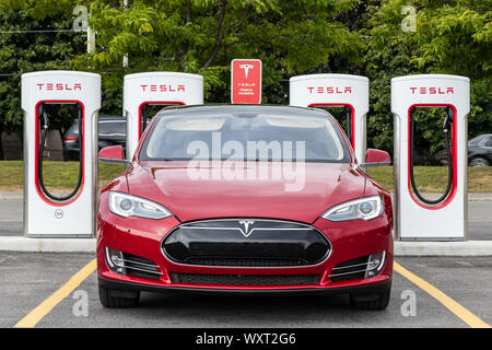 Avant du modèle Tesla S en stationnement à la station de Supercharger Tesla avec une route très fréquentée derrière. Banque D'Images