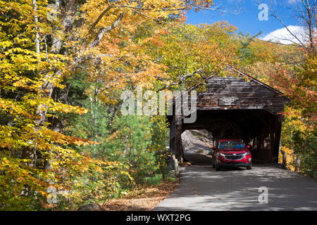 La conduite automobile pont couvert par le long de l'autoroute Kancamagus et feuillage d'automne dans les White Mountains, New Hampshire, USA Banque D'Images