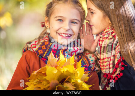 Deux cute smiling 8 ans filles discutent dans un parc sur une journée ensoleillée d'automne. Banque D'Images