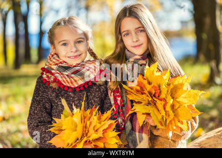 Deux cute smiling 8 ans Jeunes filles posant ensemble dans un parc sur une journée ensoleillée d'automne. Banque D'Images