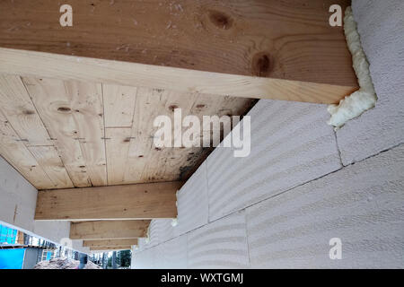 L'installation de poutres en bois de charpente avec spray foam sur le mur de la maison en construction. Banque D'Images