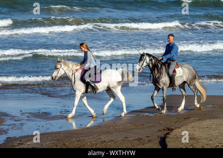 Couple de l'équitation sur une plage, littoral de la côte de l'Espagne Banque D'Images