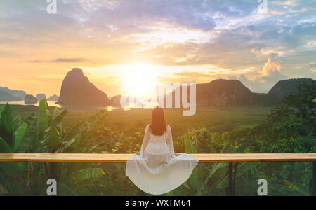 Femme à la robe blanche s'asseoir et voir la montagne tôt le matin à Samet Nangshe point de vue dans la mer d'Andaman sur matin, ciel nuageux, Banque D'Images