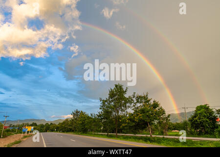 Double arc-en-ciel apparaissant après la pluie vu à partir de la route, près de la Thaïlande province de Lampang Banque D'Images