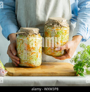 Préservation de la fermentation de la choucroute dans des bocaux en verre dans les mains d'une femme dans le milieu naturel. Traitement de la chasse d'automne. Copier l'espace. Ve en conserve Banque D'Images