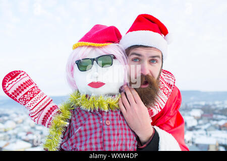 Santa man with surpris face. Hipster en rouge sur costume noël ciel nuageux. Bonhomme en rose perruque, mitaines et lunettes. Noël et nouvel an fête Banque D'Images