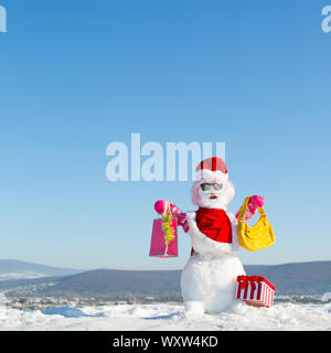 La mode d'hiver et partie. Bonnes vacances et à la fête. Le Snowman en perruque rose, mitaines, chapeau, lunettes et foulard. Cadeaux de Noël et la décoration de Noël. Nouveau Banque D'Images