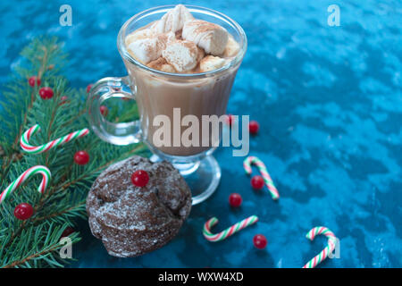 Muffin au chocolat maison de Noël décoré avec des fruits rouges et un verre de chocolat chaud sur un fond d'une branche d'arbre de Noël. Banque D'Images