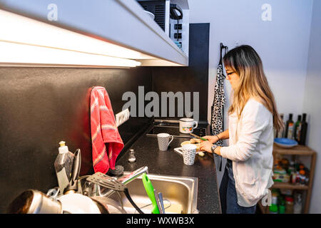 Une fille dans la cuisine prépare le thé et coupe le citron pour lui Banque D'Images