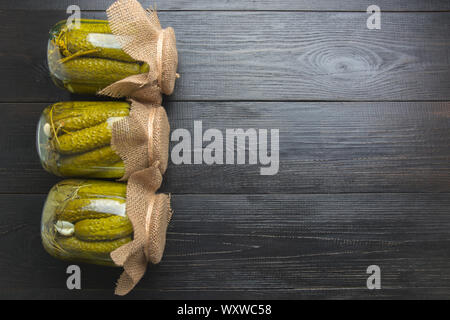 Les légumes en conserve dans des bocaux en verre de concombre sur sol en bois sombre. L'espace pour le texte. Vue de dessus. Divers types de conserves. La récolte fait maison préparation automne Banque D'Images