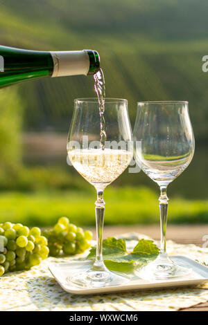 Waiter pouring qualité allemande du vin blanc riesling, produit en vin de Moselle regio raisins blancs poussant sur des pentes de collines dans la vallée de la rivière Mosel dans Banque D'Images