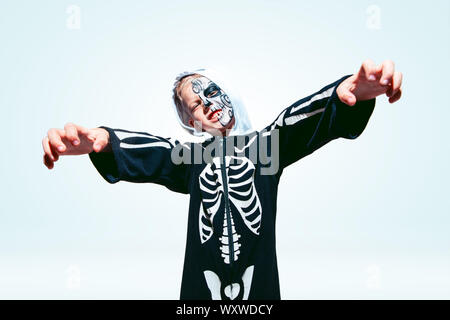 Petit garçon comme un vampire en effrayant costume noir avec des os sur fond blanc. Homme de race blanche modèle semble effrayant. Halloween, vendredi noir, vente, vacances d'automne concept. La nuit de la peur. Banque D'Images