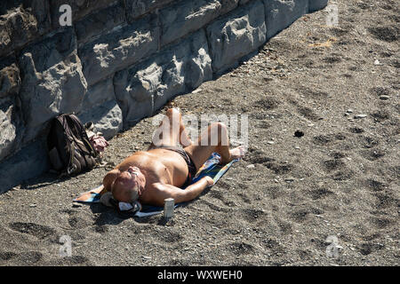 Pays de Galles Aberystwyth UK, le mercredi 18 septembre 2019 Météo France : un homme en train de bronzer sur la plage, profitant d'une journée de ciel bleu et chaud soleil de septembre au bord de mer à Aberystwyth, sur la côte de la Baie de Cardigan, l'ouest du pays de Galles, comme un système de haute pression domine la météo au cours de la moitié de l'UK souther. Crédit Photo Keith Morris / Alamy Live News Banque D'Images