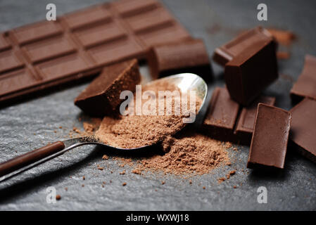 Barre de chocolat et le chocolat en poudre sur la cuillère sur le fond sombre / morceaux dessert sucré Bonbons et collations Banque D'Images