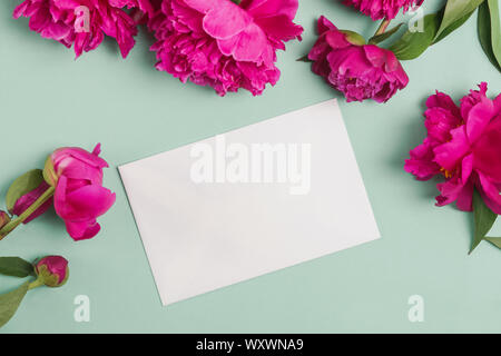 Maquette en papier rose et belles pivoines sur fond vert pastel ou de menthe, vue du dessus Banque D'Images