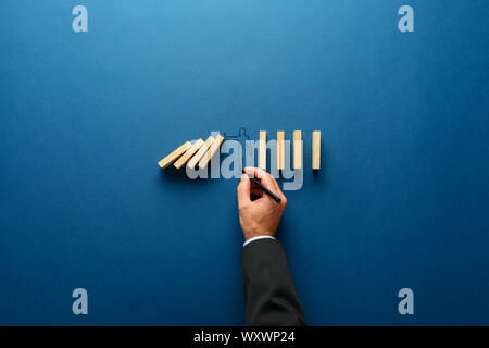 Businessman dessin silhouette d'un homme faire arrêter pour arrêter le geste de dominos de tomber dans une image conceptuelle. Sur fond bleu marine avec l'exemplaire sp Banque D'Images