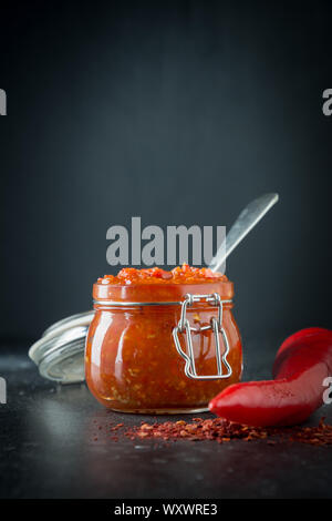 Pâte de piment bell traditionnel de la harissa sur noir.La Tunisie, géorgienne et arabes. Verticak point de vue. Banque D'Images