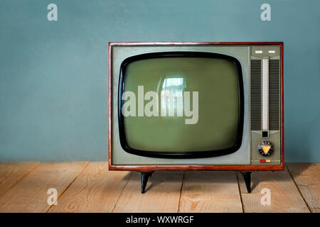 Vintage TV sur table en bois contre les old blue wall background Banque D'Images