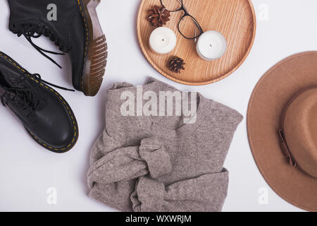 Automne féminin sur la tenue d'arrière-plan en bois blanc. Pull confortable chaud chapeau de feutre et des bottes, vue d'en haut Banque D'Images