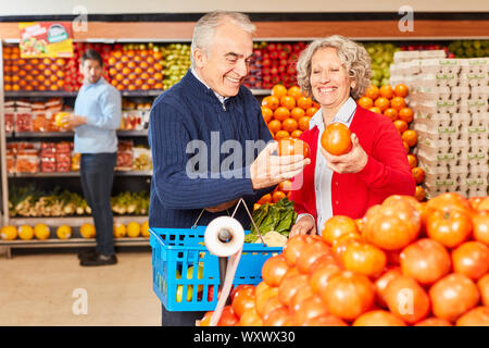 Smiling couple de personnes âgées est d'acheter des tomates au supermarché dans la section légumes Banque D'Images